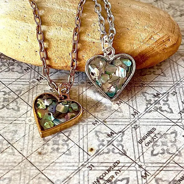 Two heart-shaped pendants filled with pieces of abalone shell, on gold and silver chains